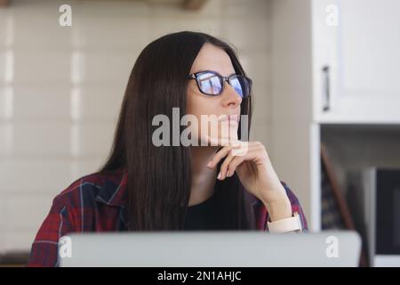 Porträt einer nachdenklichen jungen Frau in Brille, die über Problemlösung nachdenkt. Freiberufliche Frau, die in Gedanken wegschaut Stockfoto