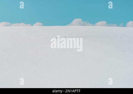 Weiße Wolken am Himmel hinter dem schneebedeckten Hügel im Winter in Zlatibor, Serbien Stockfoto