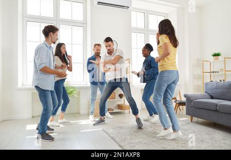 Junge, fröhliche und lustige Freunde, die tanzen und lachen, während sie sich auf einer Party treffen. Stockfoto