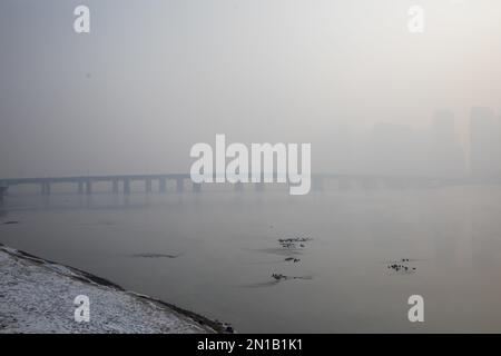 Jilin, Jilin, China. 6. Februar 2023. Am 6. Februar 2023, dem dritten Tag nach Frühling, wurde Jilin City, Provinz Jilin, Zeuge eines seltenen Naturschauspiels mit starkem Nebel, Schneeflocken, Reif und Sonnenaufgang. Gegen 9 Uhr morgens erschien plötzlich ein dichter Nebel mit einer Sicht von weniger als 50 Metern in der Stadt entlang des Songhua Flusses. Menschen, Autos und Gebäude waren vom Nebel umhüllt, der von Zeit zu Zeit verschwand und erst um mehr als 11 Uhr verschwand. Morgens schweben noch Schneeflocken am Himmel. Der Gürtel war mit Silber bedeckt, A Stockfoto