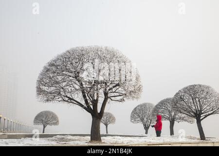 Jilin, Jilin, China. 6. Februar 2023. Am 6. Februar 2023, dem dritten Tag nach Frühling, wurde Jilin City, Provinz Jilin, Zeuge eines seltenen Naturschauspiels mit starkem Nebel, Schneeflocken, Reif und Sonnenaufgang. Gegen 9 Uhr morgens erschien plötzlich ein dichter Nebel mit einer Sicht von weniger als 50 Metern in der Stadt entlang des Songhua Flusses. Menschen, Autos und Gebäude waren vom Nebel umhüllt, der von Zeit zu Zeit verschwand und erst um mehr als 11 Uhr verschwand. Morgens schweben noch Schneeflocken am Himmel. Der Gürtel war mit Silber bedeckt, A Stockfoto