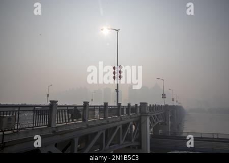 Jilin, Jilin, China. 6. Februar 2023. Am 6. Februar 2023, dem dritten Tag nach Frühling, wurde Jilin City, Provinz Jilin, Zeuge eines seltenen Naturschauspiels mit starkem Nebel, Schneeflocken, Reif und Sonnenaufgang. Gegen 9 Uhr morgens erschien plötzlich ein dichter Nebel mit einer Sicht von weniger als 50 Metern in der Stadt entlang des Songhua Flusses. Menschen, Autos und Gebäude waren vom Nebel umhüllt, der von Zeit zu Zeit verschwand und erst um mehr als 11 Uhr verschwand. Morgens schweben noch Schneeflocken am Himmel. Der Gürtel war mit Silber bedeckt, A Stockfoto