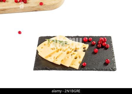Käsescheiben, Rosmarin und Cranberrys auf einer schwarzen Steinplatte. Auf weißem Hintergrund isolieren. Stockfoto