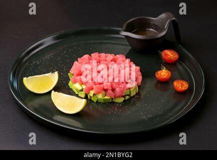 Tartar aus frischem rohem Thunfisch mit Gewürzen aus der Nähe auf einem Teller. Stockfoto