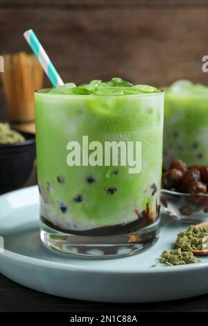 Leckerer Milchblasentee mit grüner Matcha auf blauem Teller, Nahaufnahme Stockfoto