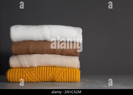 Stapel gefalteter Strickpullover auf grauem Hintergrund Stockfoto