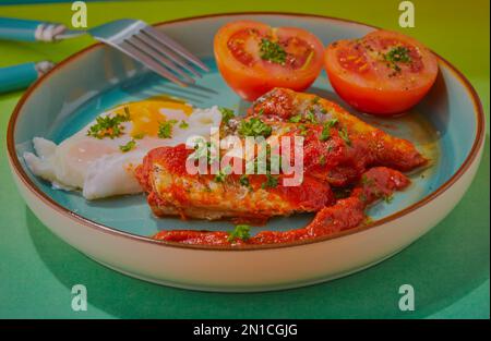 Sardinen in Tomatensoße mit pochierten Eiern und Tomaten. Stockfoto