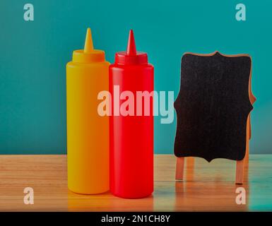 Ein paar Flaschen Tomaten- und Senfsauce auf einem Holztisch in einem Diner. Stockfoto
