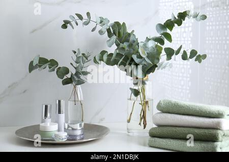 Frische Eukalyptusäste und Kosmetikprodukte auf der Arbeitsfläche im Badezimmer Stockfoto