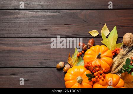 Flache Liegezusammensetzung mit Gemüse, Beeren und Herbstblättern auf Holztisch, Platz für Text. Thanksgiving-Tag Stockfoto