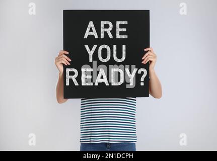 Frau mit Poster und Text: Bist du bereit? Auf hellgrauem Hintergrund Stockfoto