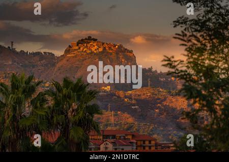 Blick auf die auf einem Hügel gelegene Stadt Castelmola bei Sonnenuntergang von Giardini Naxos, Taormina, Sizilien, Italien, Mittelmeer, Europa Stockfoto