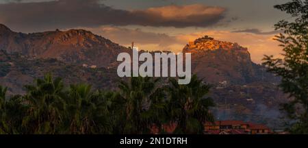 Blick auf die auf einem Hügel gelegene Stadt Castelmola bei Sonnenuntergang von Giardini Naxos, Taormina, Sizilien, Italien, Mittelmeer, Europa Stockfoto