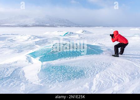 Ein Mann fotografiert die arktische Landschaft bedeckt mit Schnee auf einem gefrorenen See, Norrbotten County, Lappland, Schweden, Skandinavien, Europa Stockfoto