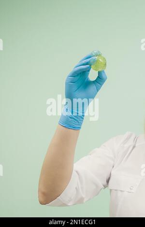 Zuckerpaste zum Shugaring in der Hand eines Kosmetikers in blauem Handschuh. Kosmetologe vor dem Enthaarungsverfahren Zuckerwachs. Stockfoto