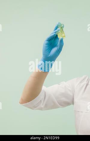 Zuckerpaste zum Shugaring in der Hand eines Kosmetikers in blauem Handschuh. Kosmetologe vor dem Enthaarungsverfahren Zuckerwachs. Stockfoto