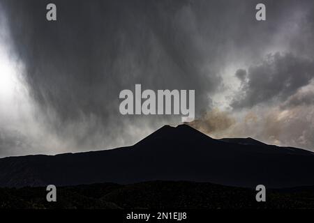 Ein dramatischer Blick auf einen heftigen Regensturm über dem rauchenden Südostkrater des Ätna in Sizilien, Europas höchstem und aktivsten Vulkan Stockfoto