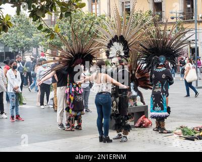 Die Menschen stehen Schlange, um traditionelle Zeremonien von indigenen Priestern in modernen Versionen der aztekischen Zeremonialkleidung, Mexiko-Stadt, Mexiko zu erhalten Stockfoto