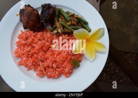 Ein Teller mit typisch indonesischem orientalischem gebratenem Reis mit gebratenem Hähnchen, isoliert auf einem weißen Teller Stockfoto