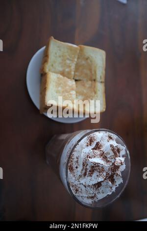 Toast mit Schokoladeneis auf einem Tisch isoliert auf einem Holzhintergrund. Stockfoto