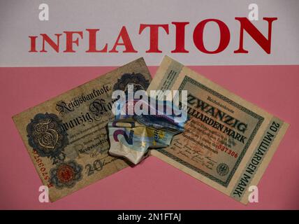 Zerknitterte 20-Euro-Banknote auf alten deutschen Mark-Banknoten mit pinkfarbenem Hintergrund, Schriftzug „INFLATION“ in großen Buchstaben oben Stockfoto