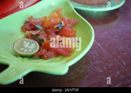 Tomate Sambal oder scharfe Tomate Sambal mit Zutaten, Schalotten, roten Chilis, Knoblauch und Salz. Serviert mit gegrilltem Fisch. Stockfoto