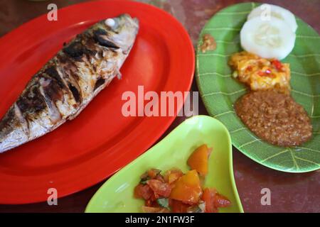 Tomate Sambal oder scharfe Tomate Sambal mit Zutaten, Schalotten, roten Chilis, Knoblauch und Salz. Serviert mit gegrilltem Fisch. Stockfoto