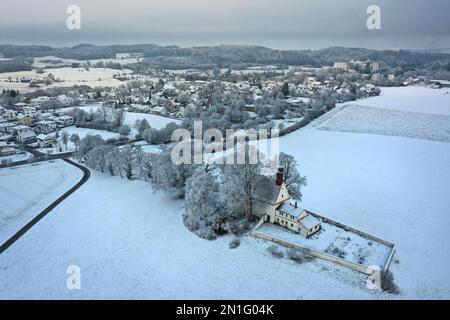 Wolfegg, Deutschland. 06. Februar 2023. Die Loreto-Kapelle ist mit Schnee bedeckt. Im Hintergrund sehen Sie den Altdorfer Wald und das Renaissance-Schloss Wolfegg. Die Burg ist der Sitz der Vorfahren des edlen Hauses Waldburg-Wolfegg. Aufgenommen mit Drohne Credit: Felix Kästle/dpa/Alamy Live News Stockfoto