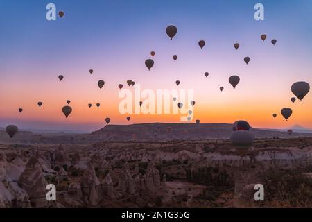 Viele wunderschöne bunte Ballons am Himmel bei einem fabelhaften Sonnenaufgang über den Felsen und Bergen in Goreme Stockfoto