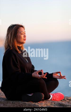 Frau, die vor Sonnenuntergang Yoga-Meditation am Meer praktiziert, als Konzept für Stille, Harmonie und Entspannung, Spanien, Europa Stockfoto