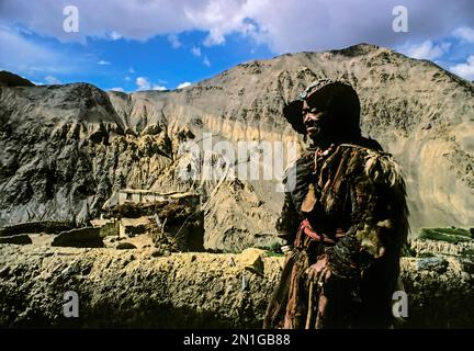 Eine alte einheimische Frau, die ein traditionelles Kopfstück mit Schmucksteinen trägt, namens Perak, vor dem heiligen Lamayuru-Kloster in Ladakh, Nordindien. Perak (Perag) ist einer von Stockfoto