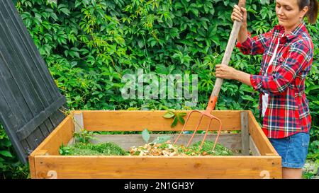 Ein Gärtner bereitet Kompost aus organischen Lebensmittelabfällen in einem selbstgemachten Holzkompost zu. Null-Verschwendung-Konzept. Das Altern des Kompost für seine Einführung in die so Stockfoto