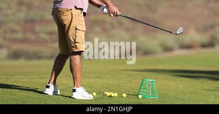 Ein Golfspieler, der mit einem Golfplatz aus Holz auf dem Fairway eine Schaukel macht Stockfoto