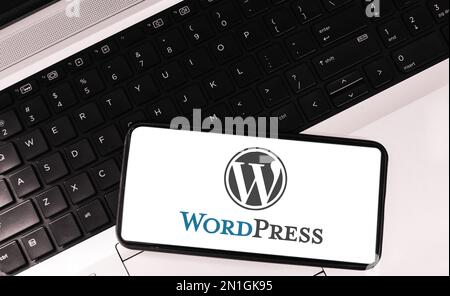 WordPress auf dem mobilen Bildschirm mit Laptop im Hintergrund, Website-Maker-Tool im redaktionellen Hintergrund Stockfoto
