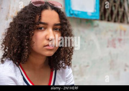 Außenporträt einer wunderschönen, durchdachten, gemischten, birassischen, afroamerikanischen Teenagerin mit Sonnenbrille Stockfoto