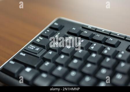 Nahaufnahme einer Computertastatur mit Feststelltaste auf einem Holz-Desktop Stockfoto