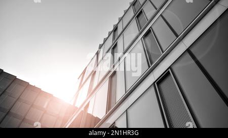 Details des modernen Wohnwohnungsappartementgebäudes von außen. Fragment eines neuen Luxushauses und Wohnkomplexes. Gelbes Sonnenlicht. Schwarz auf Weiß. Stockfoto