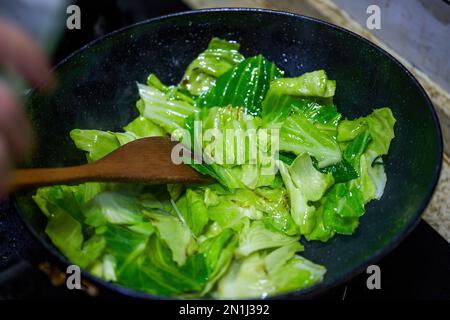 Ein chinesischer Koch brät gezerkleinerten Kohl Stockfoto