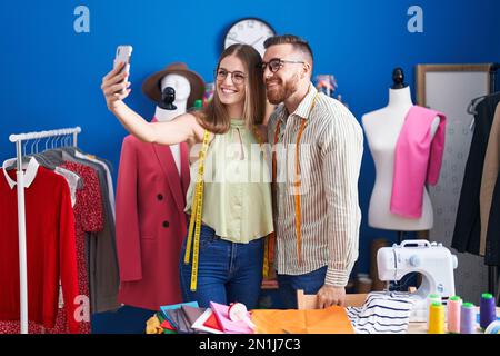 Lächelnde Männer und Frauen machen Selfies per Smartphone in der Bekleidungsfabrik Stockfoto