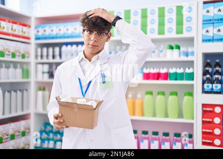 Hispanischer Teenager, der in einer Apotheke arbeitet, mit Pillen, gestresst und frustriert von Hand auf Kopf, überrascht und wütend Gesicht Stockfoto