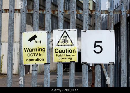 Warnung CCTV in Betrieb und Achtung Gabelstapler Betriebshinweisschilder am Außenzaun eines Industriegebäudes, Schottland, Großbritannien, Europa Stockfoto