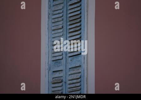 Altes ländliches Haus, hellblaue Fensterläden aus Holz mit weißen Verzierungen an einer venezianischen Stuckwand. Stockfoto