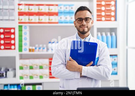 Junger hispanischer Apotheker mit Klemmbrett in der Apotheke Stockfoto