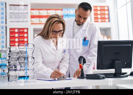 Mann- und Frauenapotheker beim Schreiben von Dokumenten in der Apotheke Stockfoto