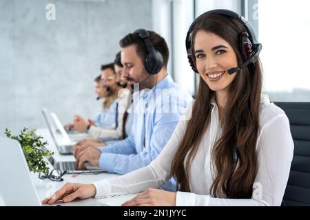 Porträt einer lächelnden jungen Callcenter-Mitarbeiterin mit Kopfhörern im Kundendienst. Stockfoto