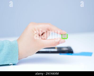 Eine Frau, die eine Micro-sim-Karte in der Hand hält Stockfoto