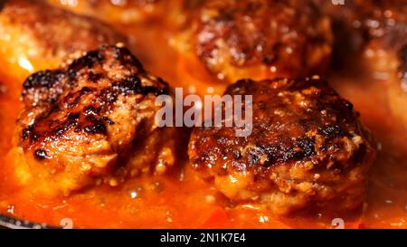 Fleischbällchen mit kochender Tomatensoße in der Pfanne Zubereitung leckeres Essen. Kochen in der Hausküche. Selektiver Fokus. Schließen. Stockfoto