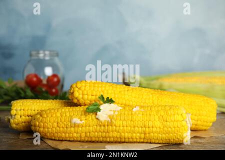 Frische Maiskolben mit Butter auf Holztisch Stockfoto