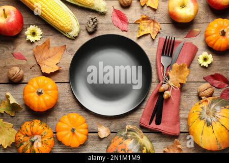 Flache Liegezusammensetzung mit Geschirr, Herbstobst und Gemüse auf Holzhintergrund. Thanksgiving-Tag Stockfoto