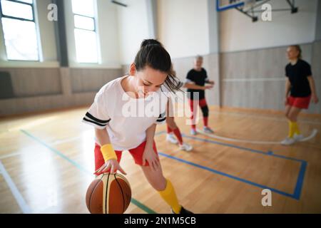 Frauen mit mehreren Generationen spielen im Fitnessstudio ein Basketballspiel. Stockfoto